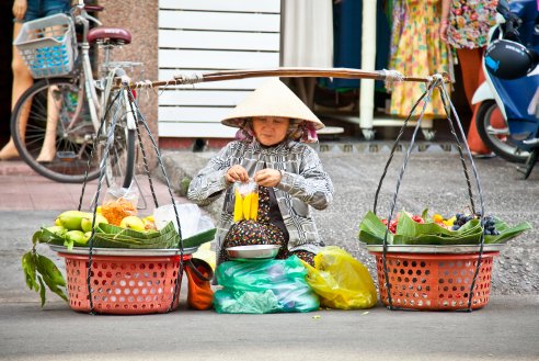 A picture of a woman in Hanoi, Vietnam with baskets full of fruit 