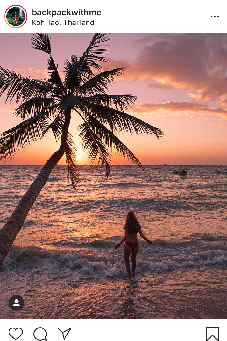 Girl walking into the sea with pink sunset and palm trees