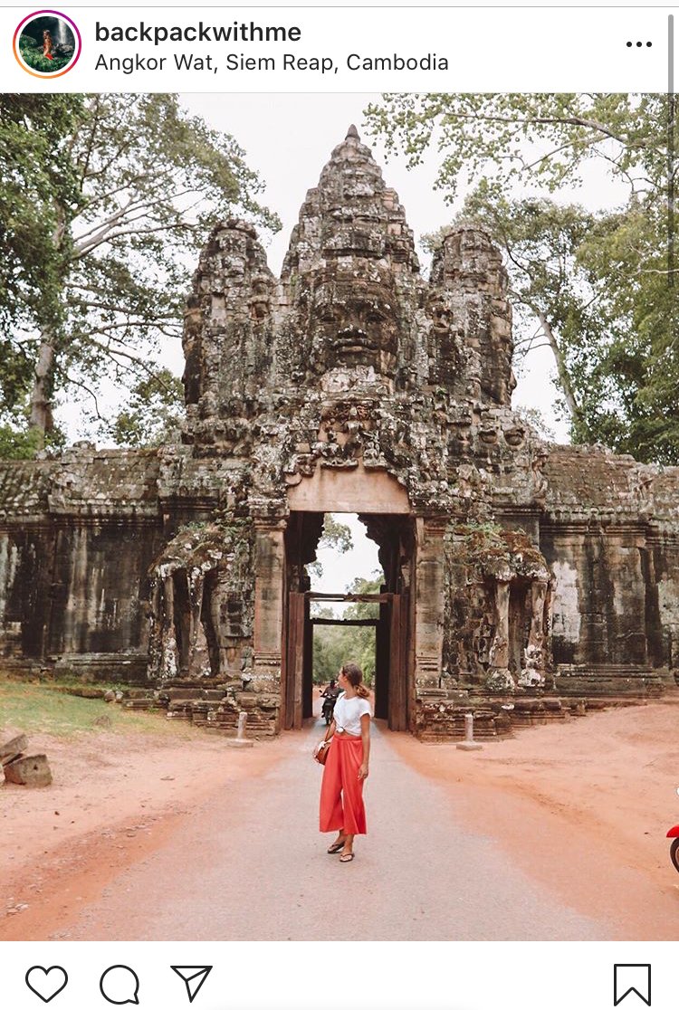 Girl walking into Angkor Wat temple in Cambodia with trees around