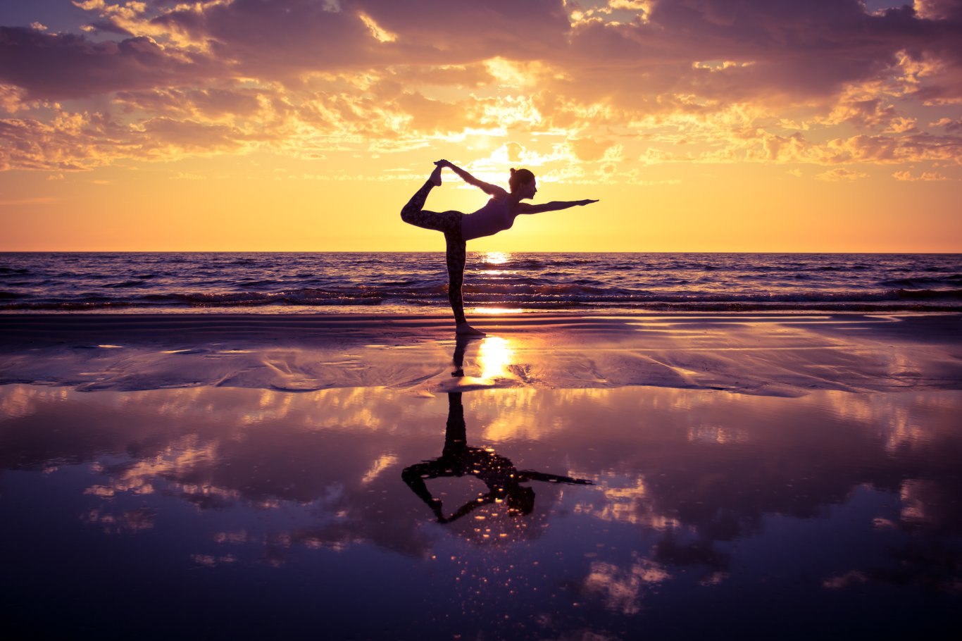 A photo someone practicing yoga at the beach at sunset 