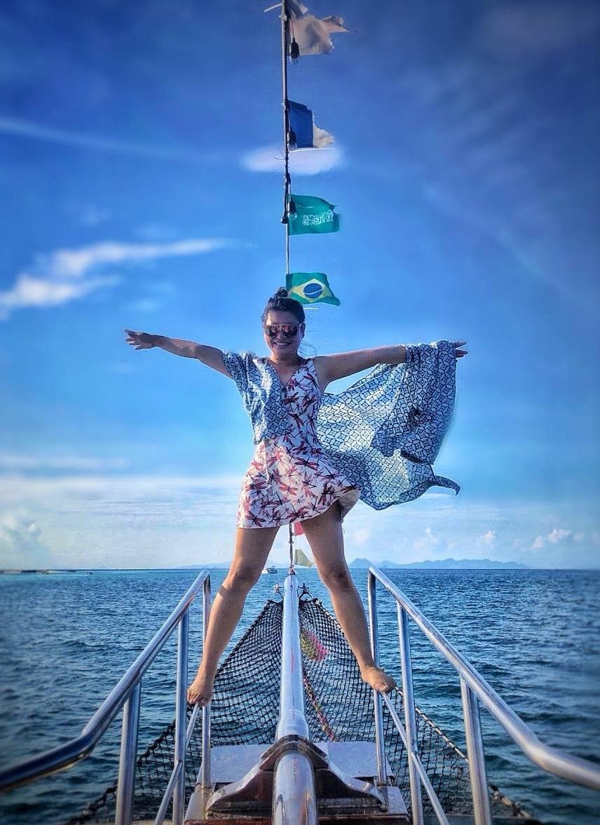 Girl with hands in the air on the top of a boat in titanic pose with sea in the background