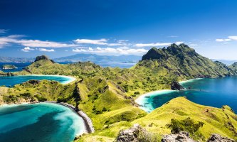 A view of Padar Island showing lush green hills, white sand beaches and the bright blue ocean