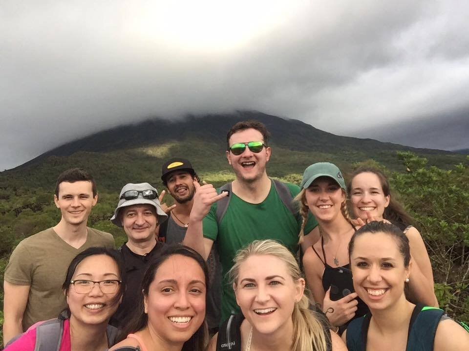 Group of Young Travellers smiling with Volcano in distance and fog rolling in
