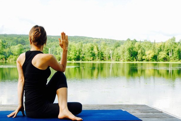 A women practicing yoga by a serene lake 