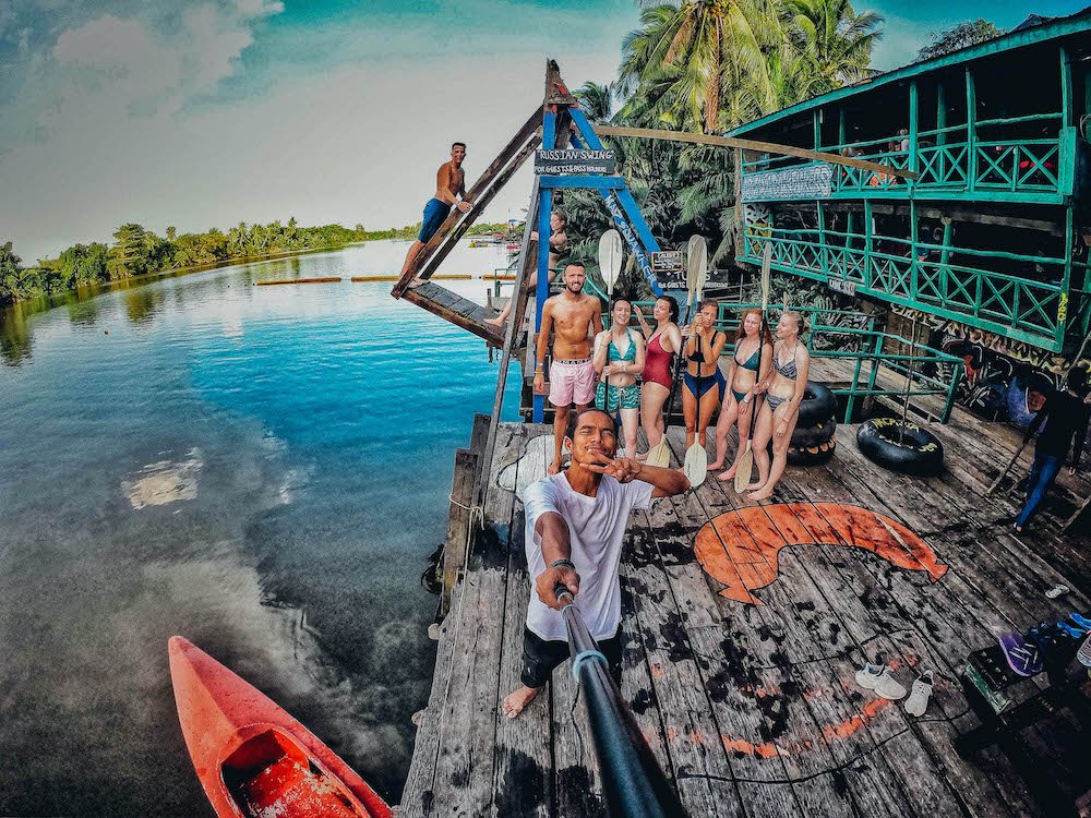 Group of young Travellers on River with Kayaks and Jumping Platform