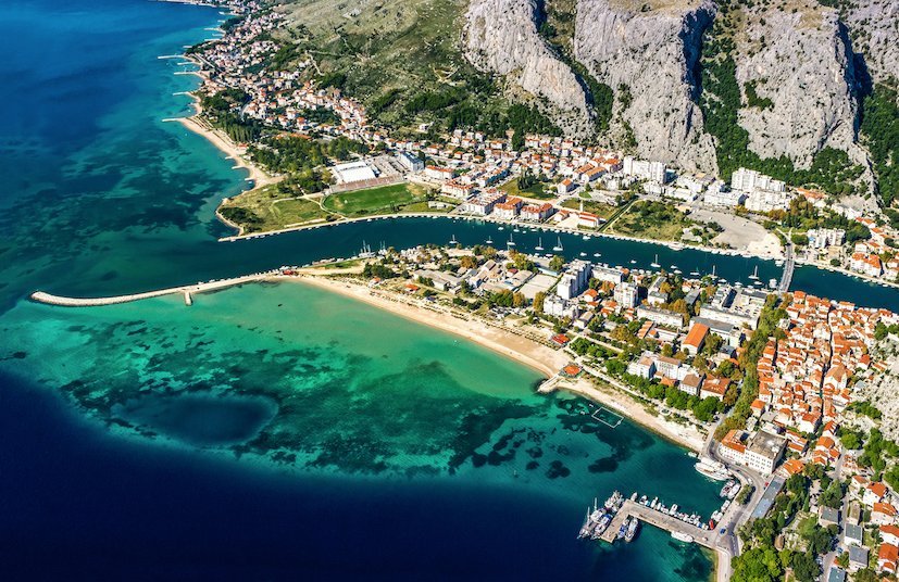 A birds eye view photo of Omis, Croatia showing the different shades of the sea, the stunning landscape and town