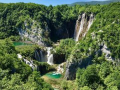 A gorgeous photo of the Plitvice falls in Croatia, showing the lush greenery of the national park and the bright turquoise waters.