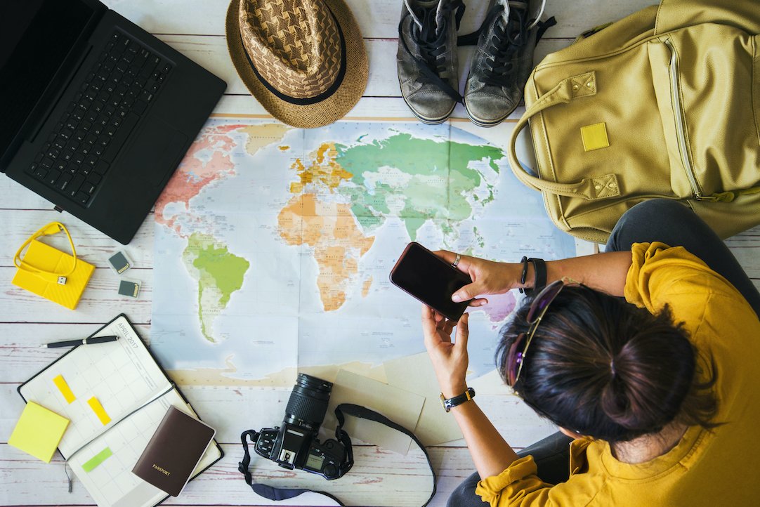 Girl sitting down with Map and Travel Essentials planning trip