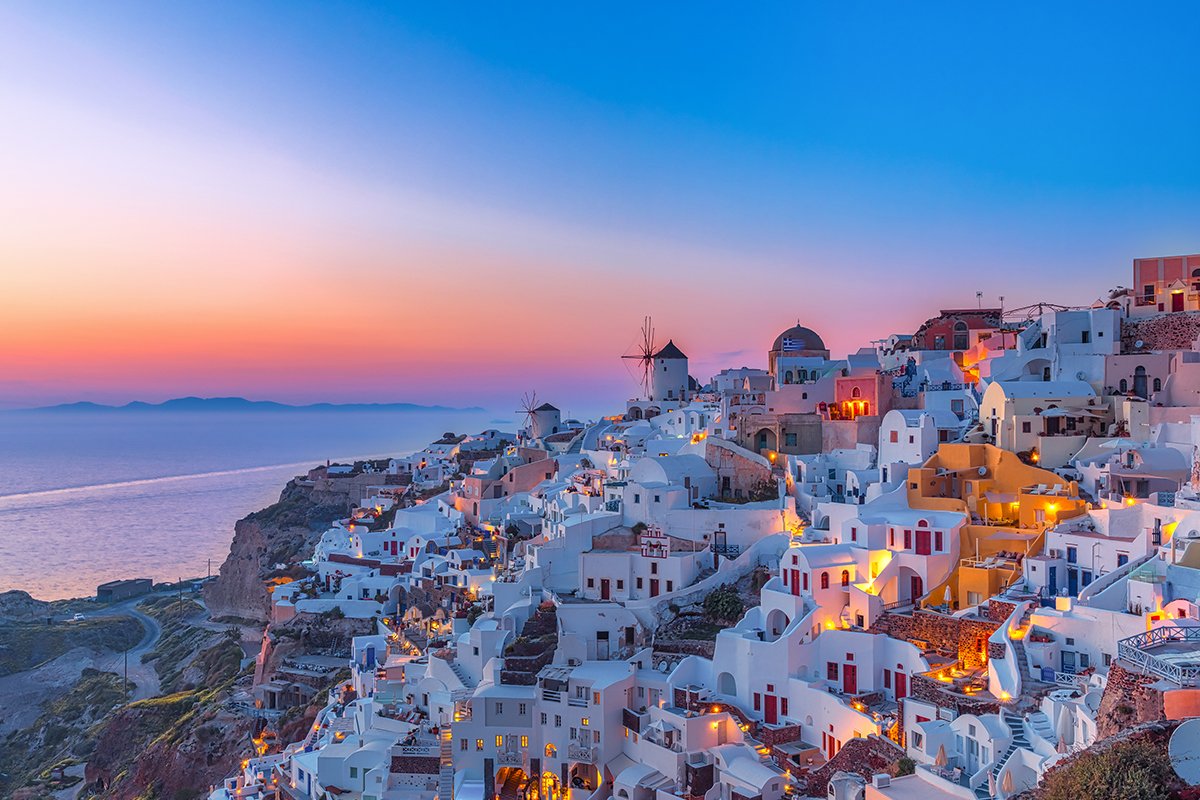 A view of the beautiful orange and pink sunset hitting the white villas in Santorini Greece