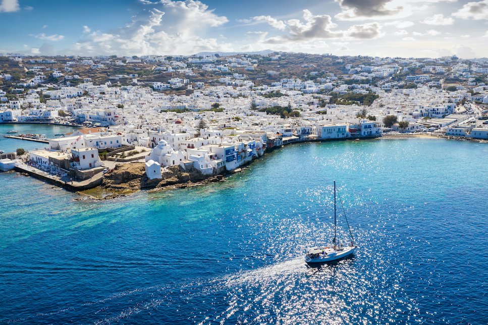 Birds Eye View of Naxos Greece with Sailboat and gorgeous blue Ocean with whitewashed buildings