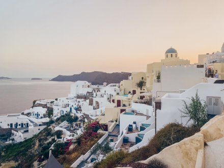 A photo of the famous white architecture in Santorini at sunset, with the sea and mountains in background