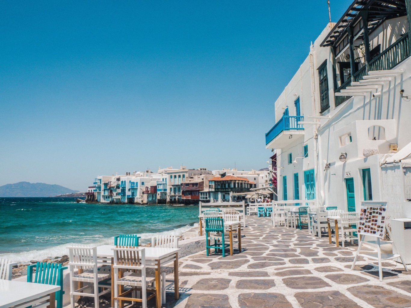 A photo of white and blue houses along the bright blue waterfront in Paros, Greece