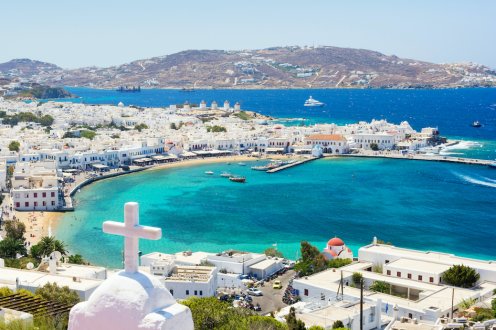 A scenic view of Mykonos, Greece showing the white Greek architecture, the vibrant clear blue ocean and surrounding landscapes