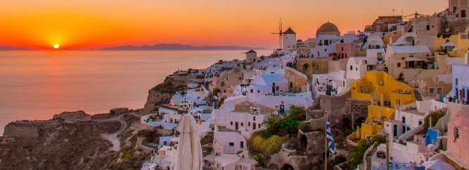 A banner for Greece showing a gorgeous golden orange sunset over the white houses in Oia, Santorini, Greece 