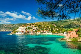 An incredible photo of the clear turquoise water, the greenery and houses on the water in Kassiopi Greece