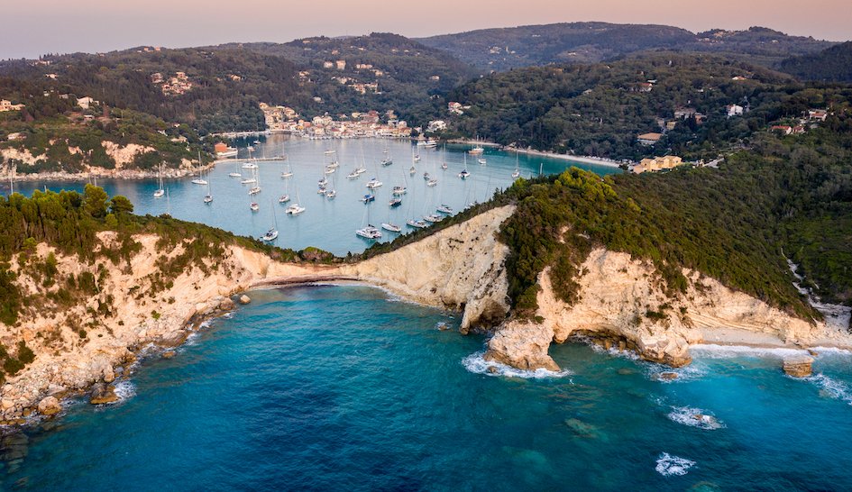 A stunning aerial view of the coast at sunset with bright blue water in Lakka, Paxos, Greece 