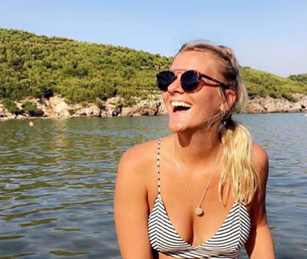 Girl wearing sunglasses laughing sat at sea