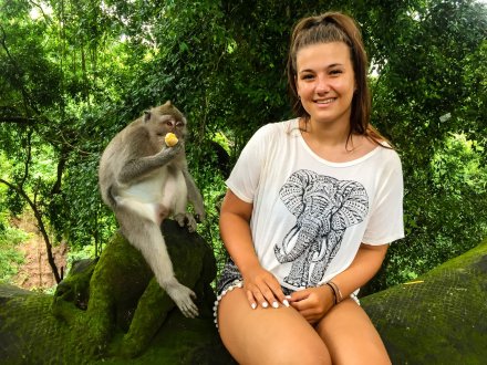 Girl sat in jungle with a monkey