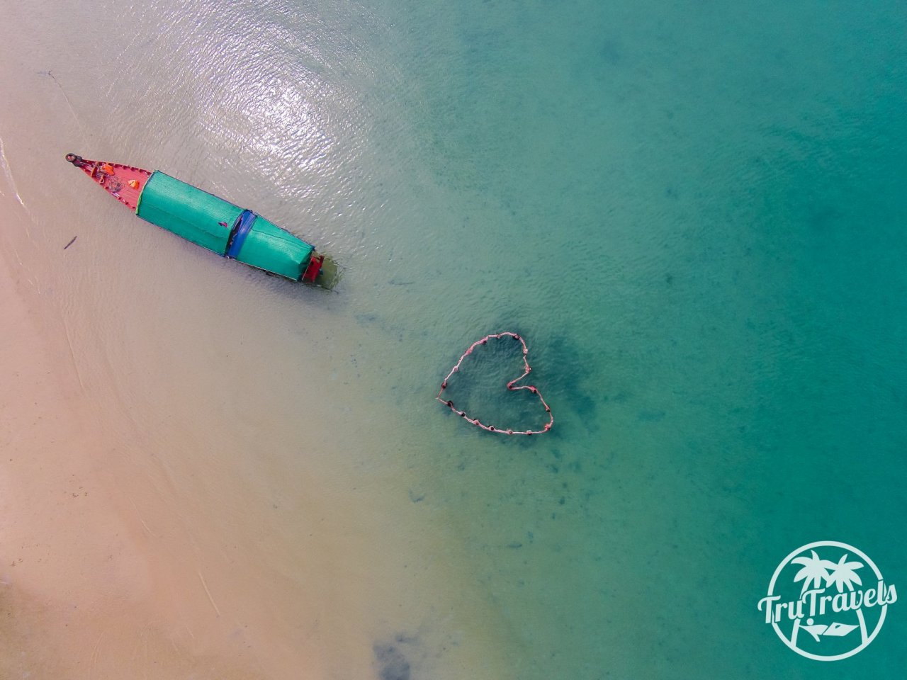 Birds eye view of blue sea, boat and people in love heart shape