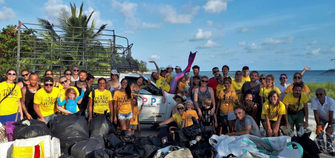 Large group of people on beach with bin bags wearing yellow t shirts