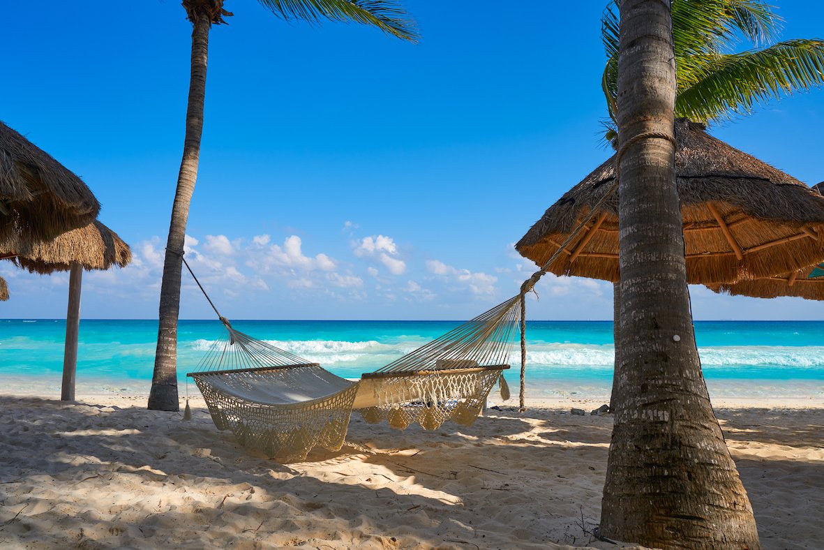 Hammock on beach with blue sea and sky behind