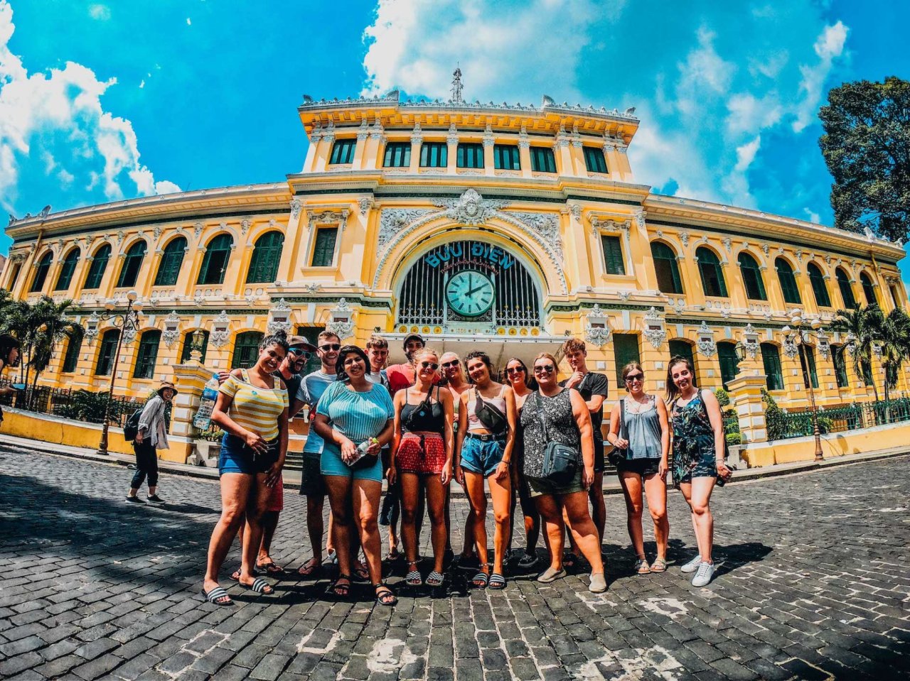 Group of travellers in front of yellow building on cobbled streets