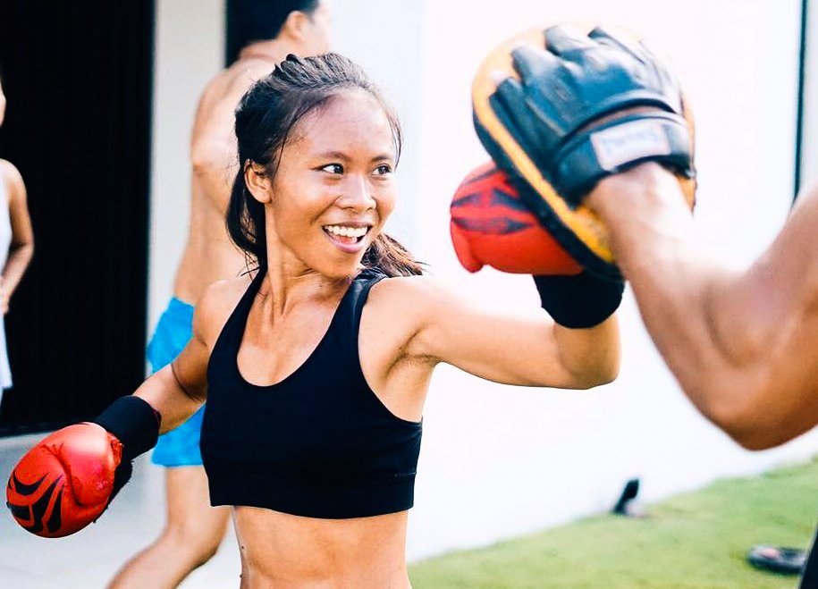 A girl wearing boxing gloves taking part in a boxing class in Bali, Indonesia 