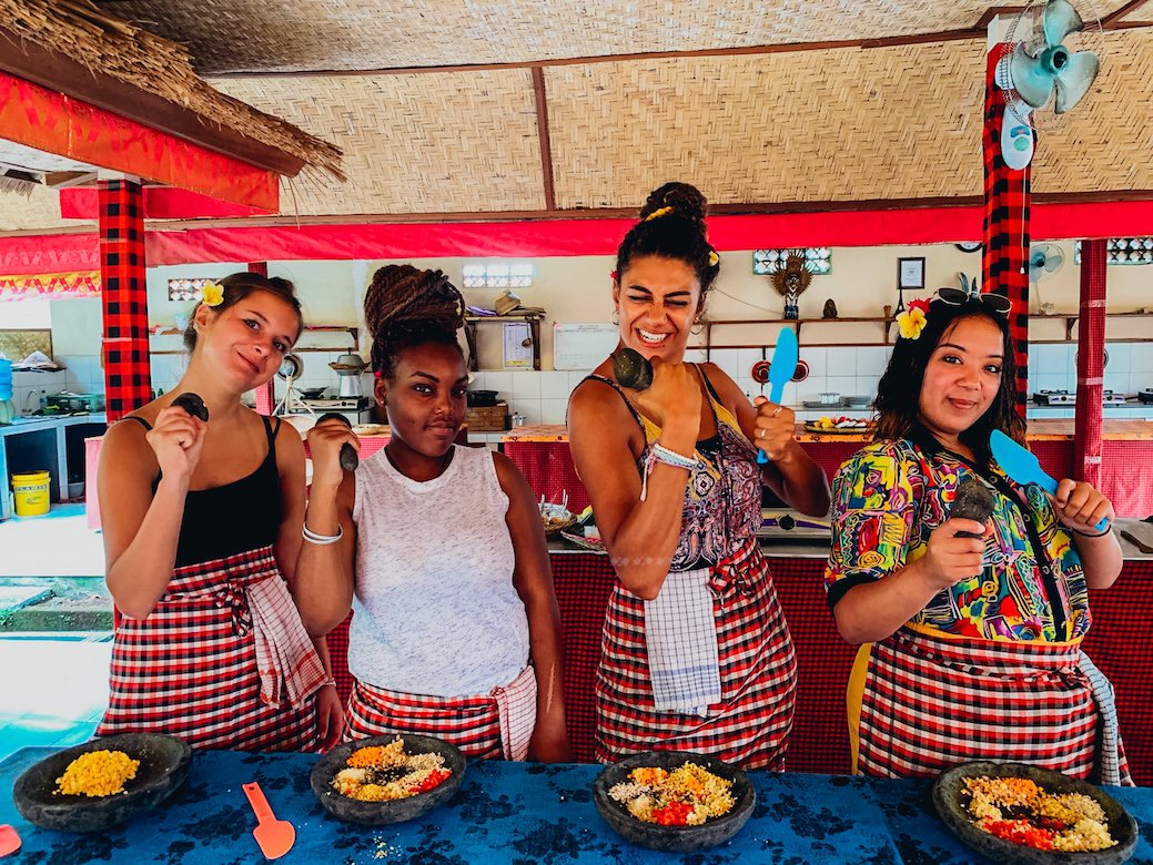 Four girls wearing aprons while taking part in a traditional Balinese cooking class in Bali, Indonesia 