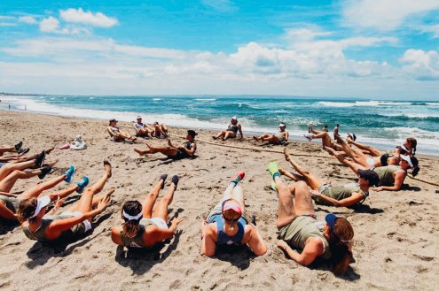A shot of a group doing a HIIT workout on the beach in Bali,Indonesia with the bright blue sea and sky in the background
