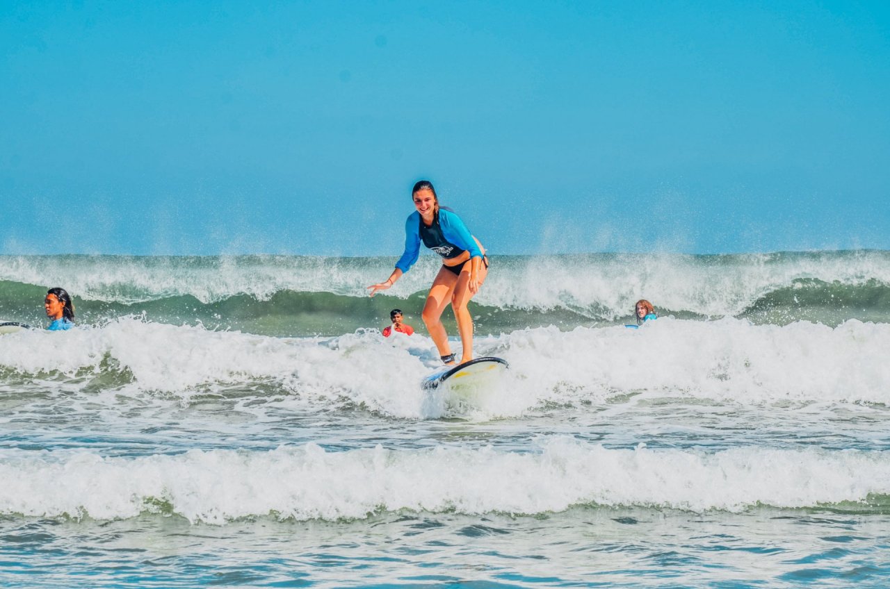 A girl surfing waves with a bright blue sky in the background in Bali, Indonesia 