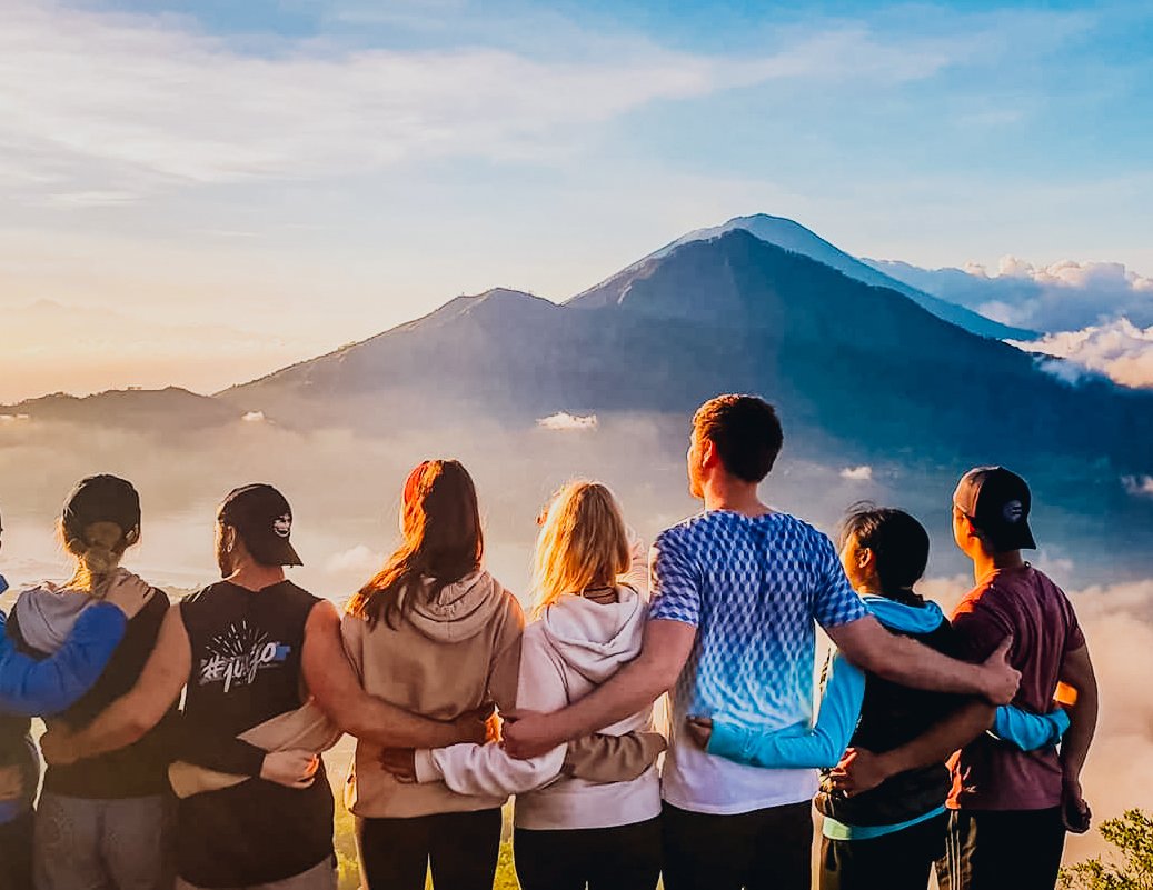 A group admiring the view of the sunrise and clouds at Mount Batur, Indonesia 