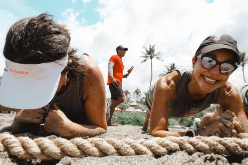 Two girls doing the plank while taking  a HIIT workout class on the beach in Bali, Indonesia 