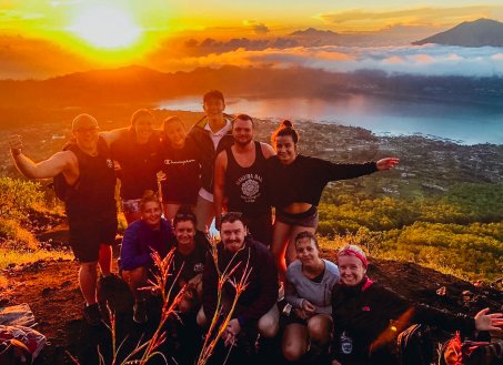A group shot in front of the bright orange and golden sunrise while hiking Mount Batur in Bali, Indonesia 