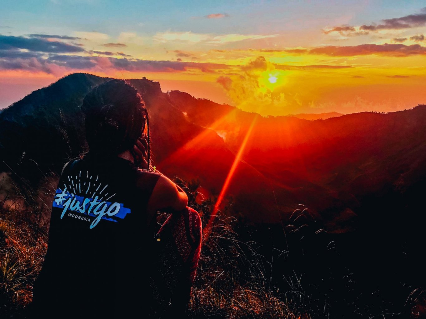 A shot of someone sitting and watching the sunrise over the mountains after hiking Mount Batur in Bali, Indonesia 