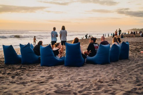 people sat in a circle of blue beach bean bags with sea behind