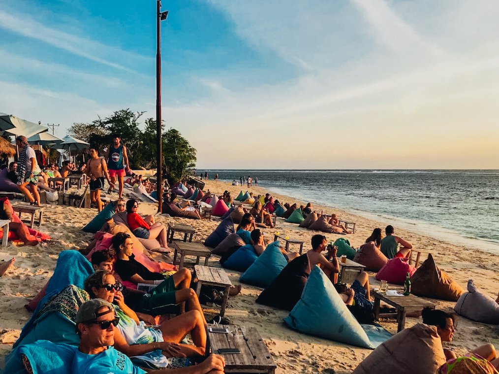 People sat on colourful beach bags on beach looking out to sea