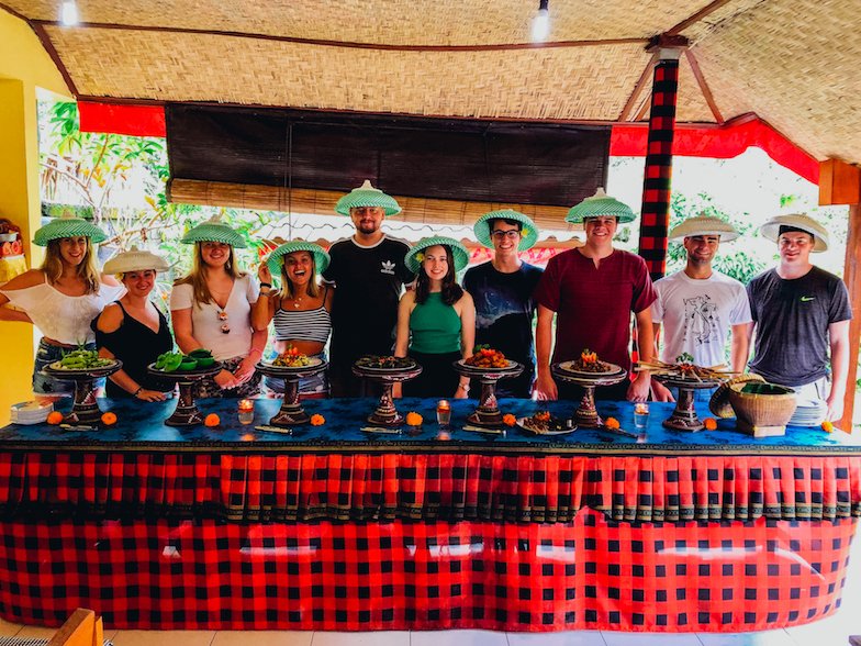 Group of people stood behind table full of food with green hats on