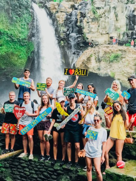 Group photo at Ubud waterfall holding colourful signs