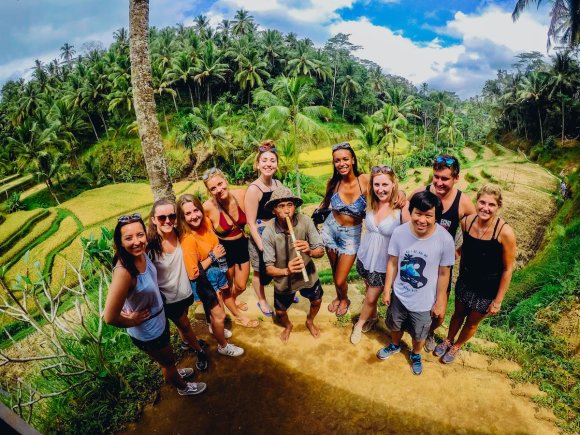 Group of travellers at Ubud rice terraces smiling with green trees in background 