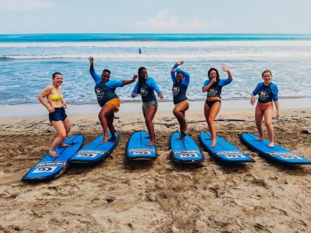 A group practicing their moves on their surf boards before heading into water for a lesson at Kuta beach Bali