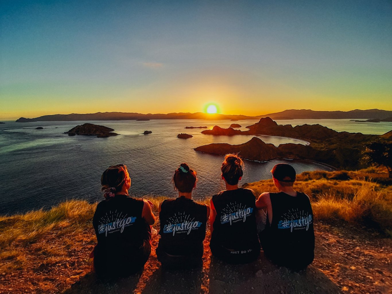 A group watching the orange sunset at the incredible viewpoint on Padar island in Indonesia