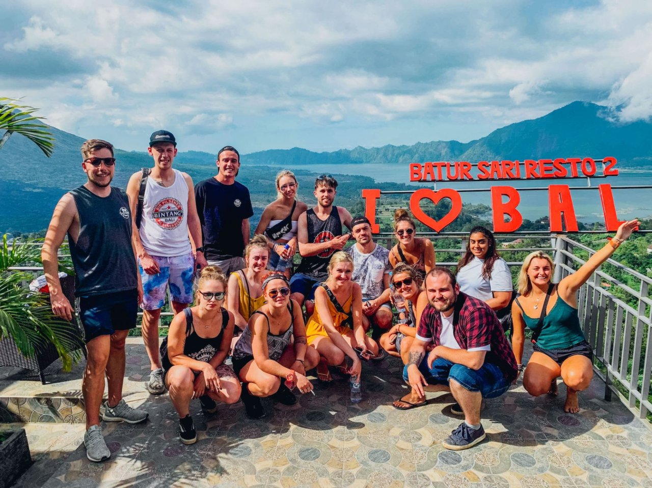 A group sat in front of a red ''I love Bali'' sign by Mount Batur in Bali, Indonesia 