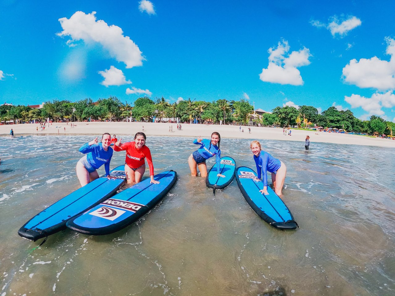 A group of four pushing their surf boards into the sea ready for a surfing lesson in Canggu, Bali, Indonesia 