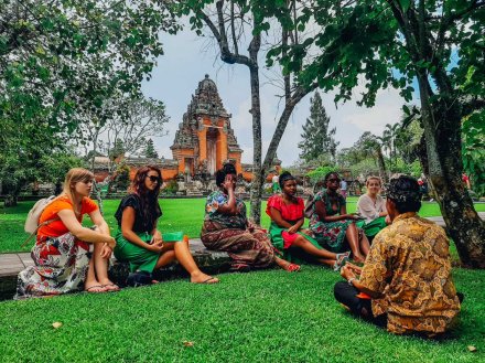 A group at the temple Taman Ayun, sat on the grass in Bali, Indonesia 