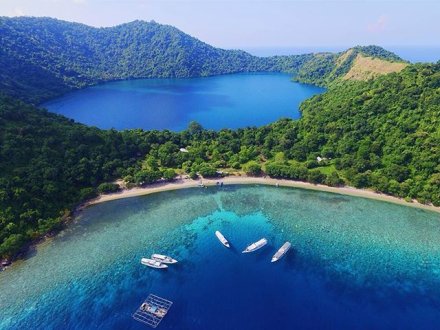 A stunning aerial shot of Satonda Island, Sumbawa in Indonesia showing the salt water lake, lush greenery and bright blue clear ocean