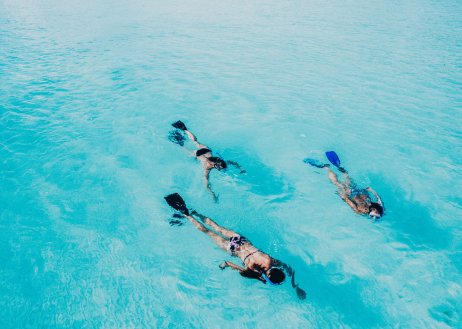 An above the water shot of a group of three while snorkelling the crystal clear blue ocean in the Maldives
