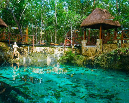 A bright blue turquoise natural pool surrounded by luscious greenery in Mexico  