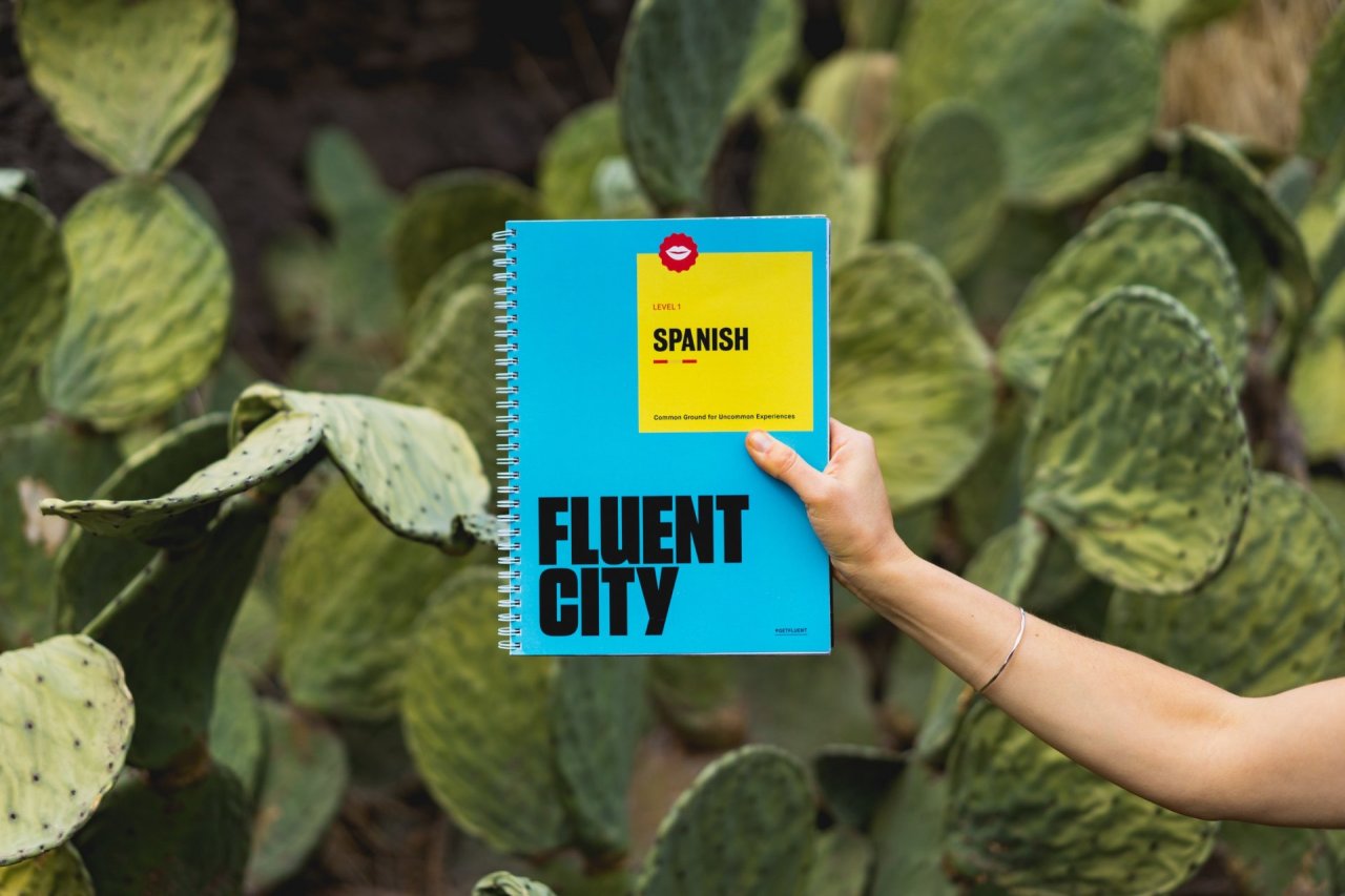 Cacti with Arm holding Notebook with Spanish Fluent City written on it