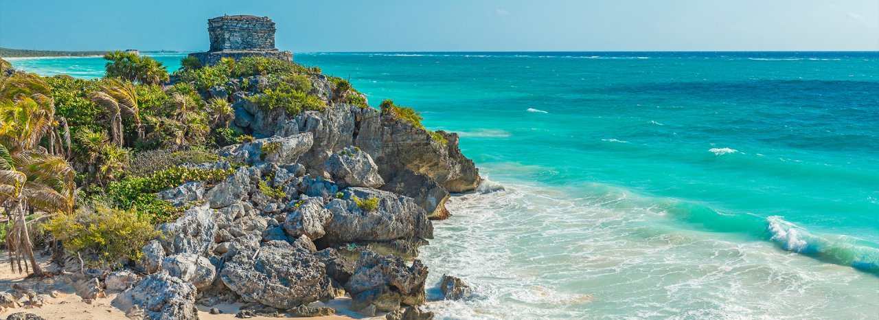 A banner for Mexico showing the ancient ruins in Tulum, Mexico and the bright clear blue ocean