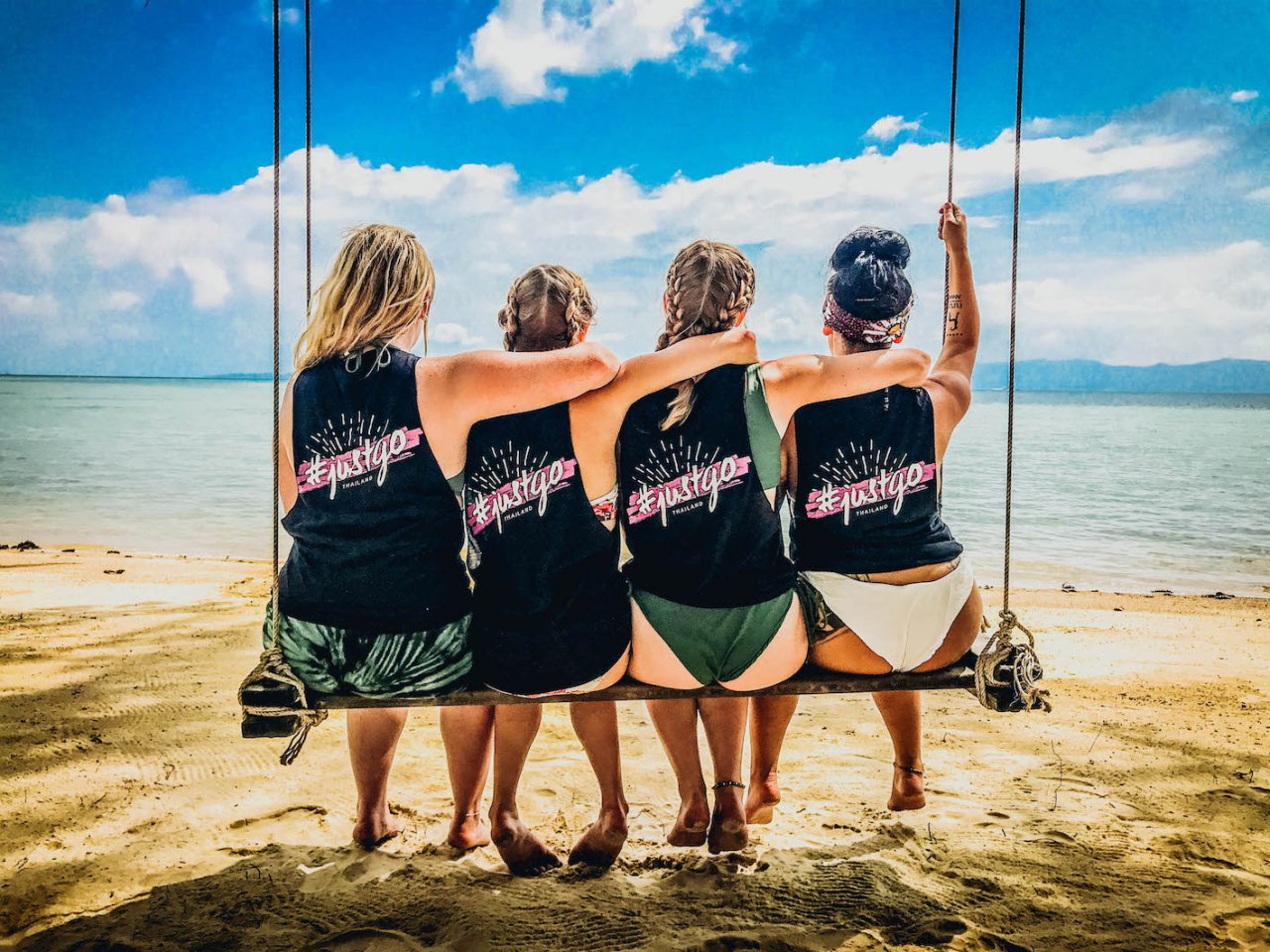 Four girls sitting on a swing at bottle beach Koh Phangan Thailand